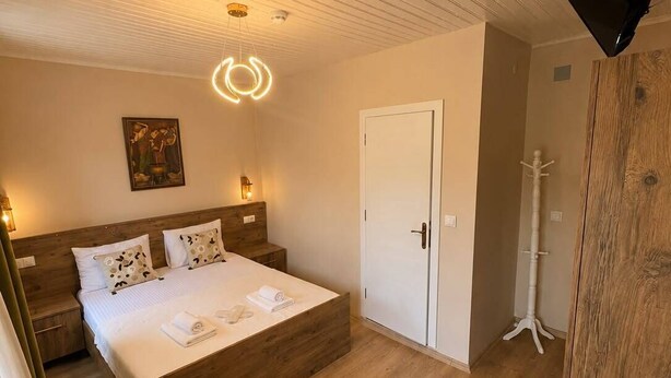 Un dormitorio con una cama de madera, una puerta blanca y un cuadro en la pared.
