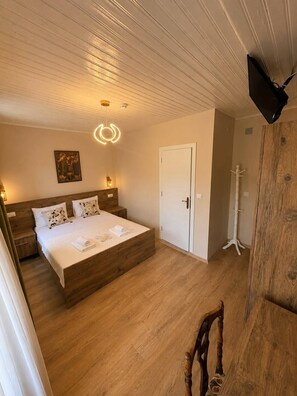 A bedroom with a wooden bed, a white door, and a painting on the wall. - Anjea Otel  (Çeşme)