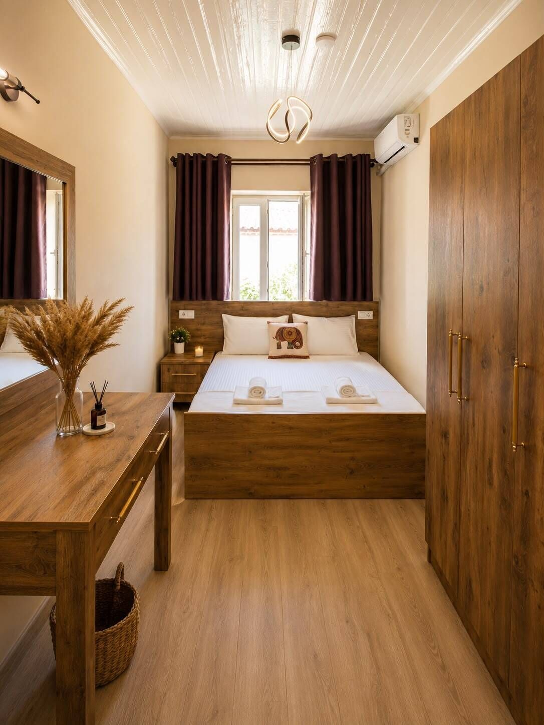 A bedroom with a wooden bed, a bedside table with a vase and candles, a mirror, and a wardrobe.