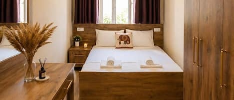 A bedroom with a wooden bed, a bedside table with a vase and candles, a mirror, and a wardrobe.