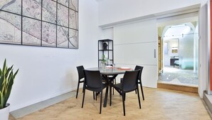 Uma área de refeições com uma mesa redonda, cadeiras pretas, uma planta em vaso e um grande mapa abstrato na parede.