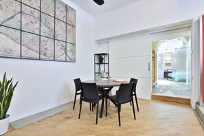 Ein Essbereich mit einem runden Tisch, schwarzen Stühlen, einer Zimmerpflanze und einer großen abstrakten Weltkarte an der Wand.