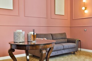 Ein Zimmer mit einem runden Holztisch, einem grauen Sofa und einer Wandleuchte.