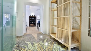 Um corredor com piso de azulejos, uma estante de madeira e uma porta de vidro.