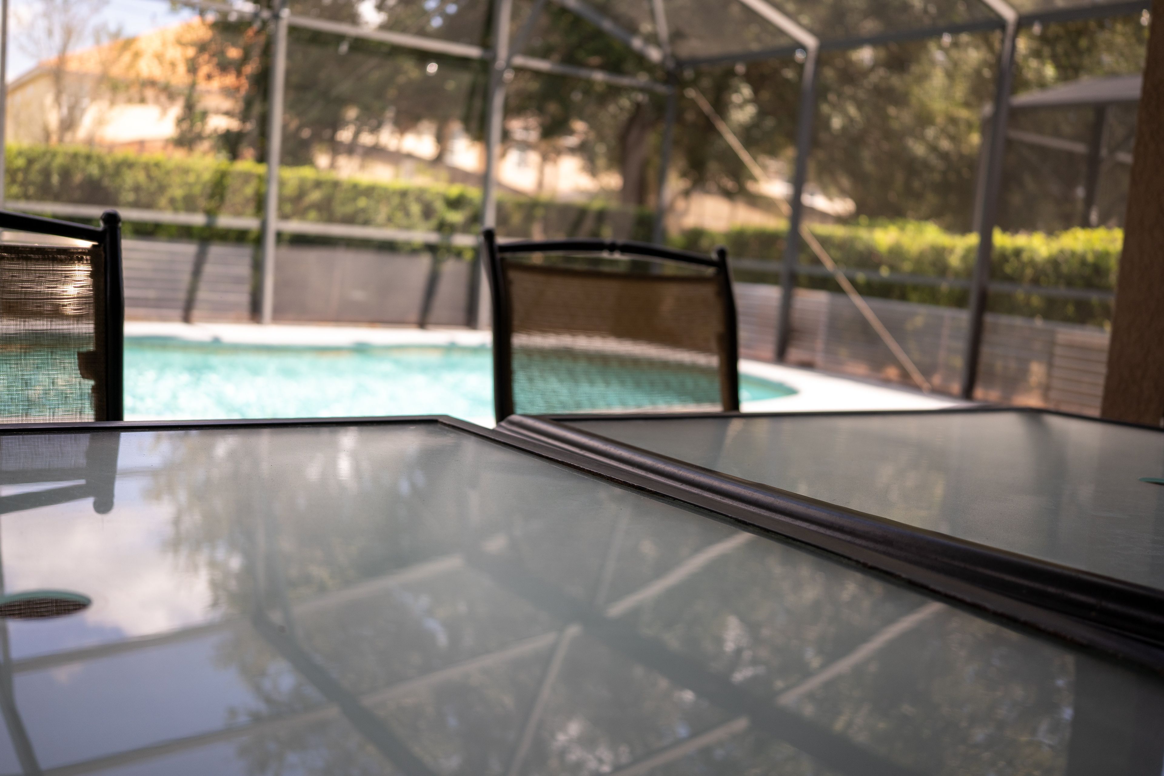 A clear glass table with a pool in the background.