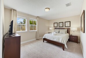 A bedroom with a bed, bedside tables, a desk, and a television. - Luxury Solterra Resort Retreat | Near Disney (Davenport)