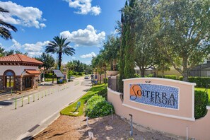 A sign for Solterra Resort with a clear view of the surrounding area including a road, greenery, and a building with a tiled roof. - Luxury Solterra Resort Retreat | Near Disney (Davenport)