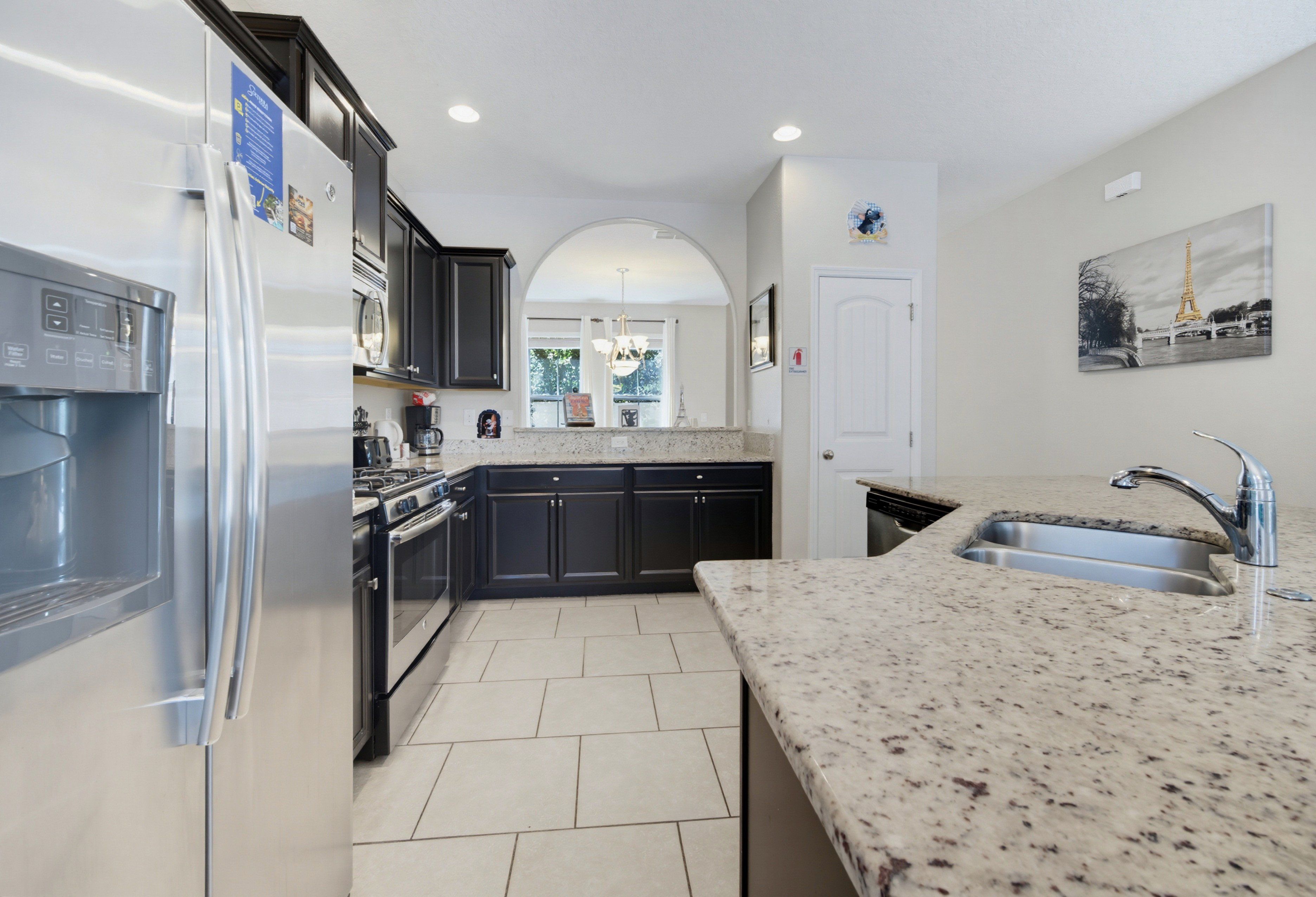 A modern kitchen with a stainless steel refrigerator, a built-in oven, and a granite countertop.