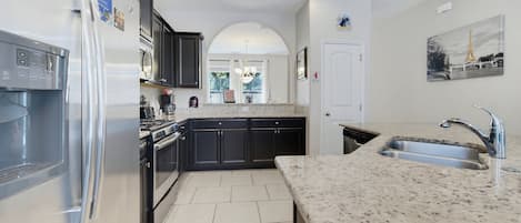 Una cocina moderna con un refrigerador de acero inoxidable, horno empotrado y encimera de granito.