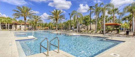 A large outdoor swimming pool with multiple lanes, surrounded by palm trees and lounge chairs.