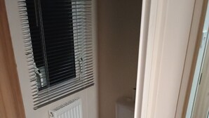 Ett litet badrum med en toalett, ett handfat och ett fönster med persienner.