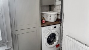 A compact laundry room with a washing machine, a drying rack, and a cabinet. - Sleeps 10 3 Bed Central Grantham with Parking (Grantham)