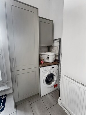 A compact laundry room with a washing machine, a drying rack, and a cabinet. - Sleeps 10 3 Bed Central Grantham with Parking (Grantham)