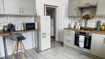 A modern kitchen with white cabinets, a refrigerator, a microwave, and a coffee machine.