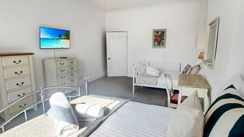 A bedroom with a bed, bedside tables, a dresser, a television, and a ceiling light.