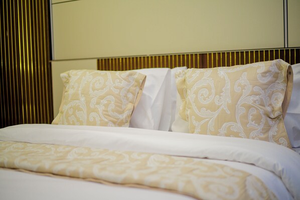 A hotel room with a bed, two pillows with a paisley pattern, and a headboard with vertical slats. - JOSEPHINA LODGE DODOMA (Dodoma)