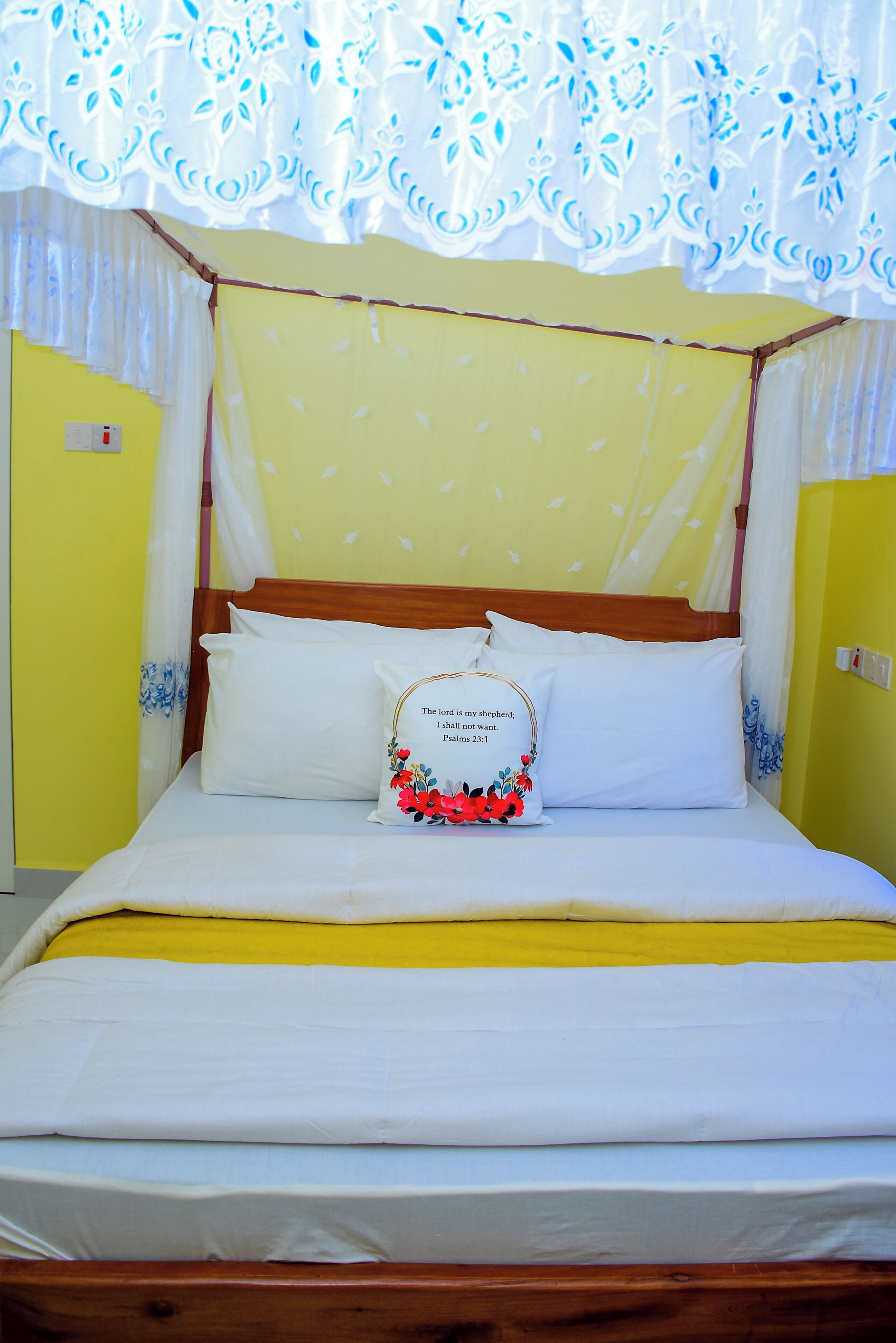 Ein Bett mit Baldachin, ein Kissen mit Blumenmuster und eine gelbe Bettdecke.