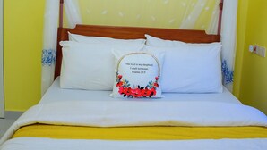 Un letto a baldacchino, un cuscino con motivo floreale e una coperta gialla.