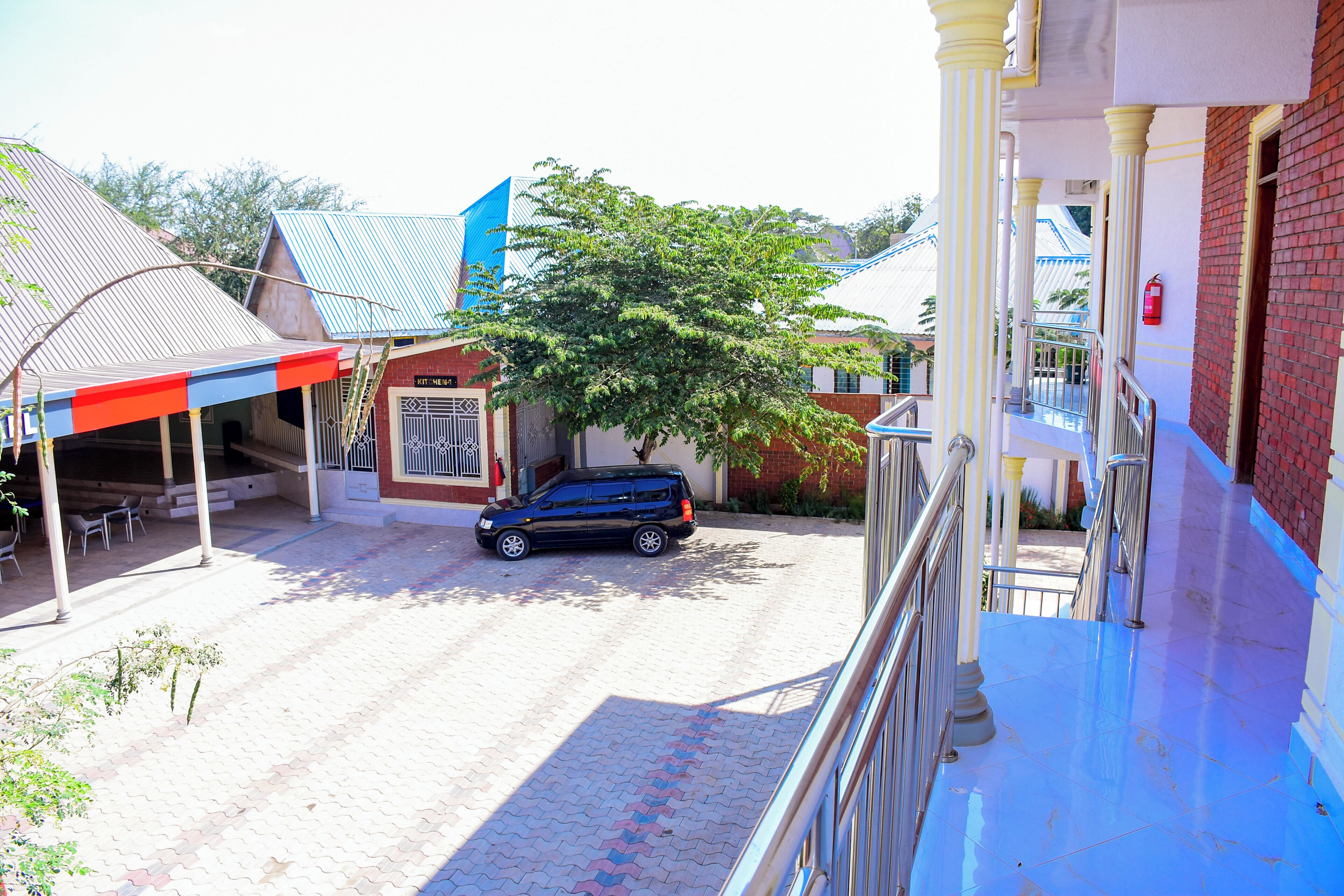 A building with a blue awning, a parked car, and a tree in front.