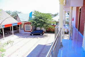 Um edifício com toldo azul, um carro estacionado e uma árvore em frente.