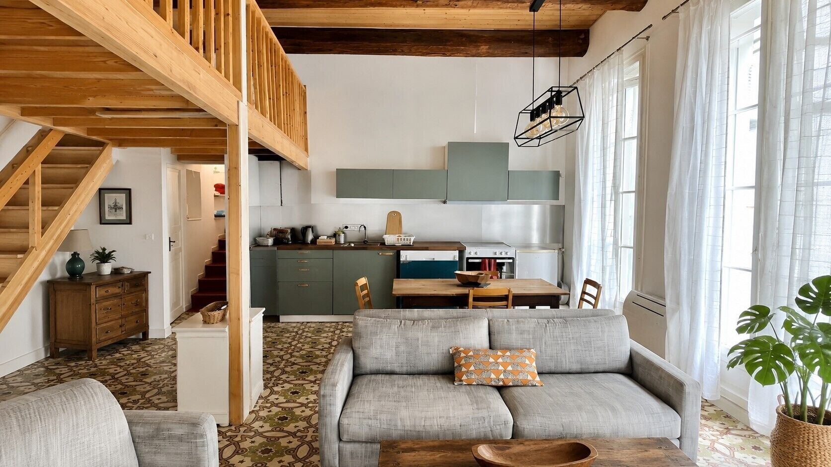 A cozy living room with a sofa, a wooden dining table, and a kitchen in the background.