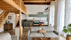 Una sala acogedora con un sofá, una mesa de comedor de madera y una cocina al fondo.