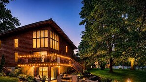 Ein zweistöckiges Holzhaus mit Terrasse, Sitzgelegenheit im Freien und einem Whirlpool.