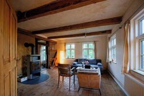 A rustic room with exposed wooden beams, a fireplace, a sofa, and a chair. - 18th-century half-timbered house in Lutter (Langelsheim)