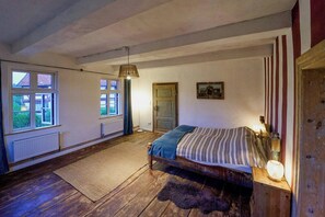 A bedroom with a wooden bed, a radiator, a window, and a door. - 18th-century half-timbered house in Lutter (Langelsheim)