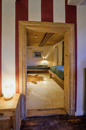 A narrow hallway leading to a bedroom with a bed and a nightstand. - 18th-century half-timbered house in Lutter (Langelsheim)