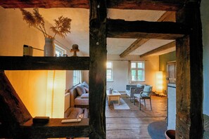 A cozy living room with a sofa, a coffee table, and a lamp. - 18th-century half-timbered house in Lutter (Langelsheim)