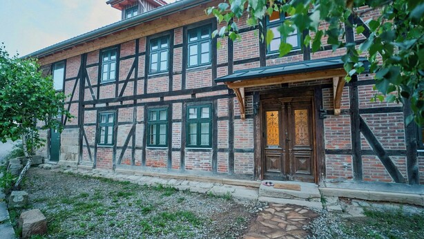 Ein traditionelles Fachwerkhäuschen mit Holztür und mehreren Fenstern.
