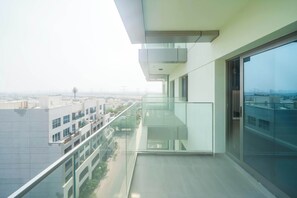 A modern balcony with a glass railing overlooking a cityscape. - Tranquil Wellness Stay  Modern Hotel Apartment (Jumeirah Village Triangle)
