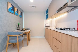 A compact kitchen with a dining area, wooden cabinets, and a modern stove. - Tranquil Wellness Stay  Modern Hotel Apartment (Jumeirah Village Triangle)