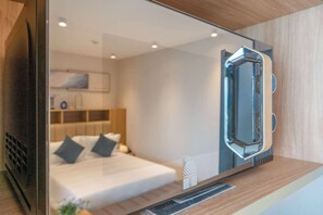 Ein modernes Hotelzimmer mit einem Bett, einem Nachttisch und einem an der Wand montierten Fernseher.