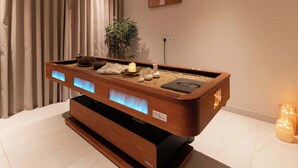 Ein Massagetisch aus Holz mit integriertem Massagekopf, einer Kerze und einer kleinen Pflanze.