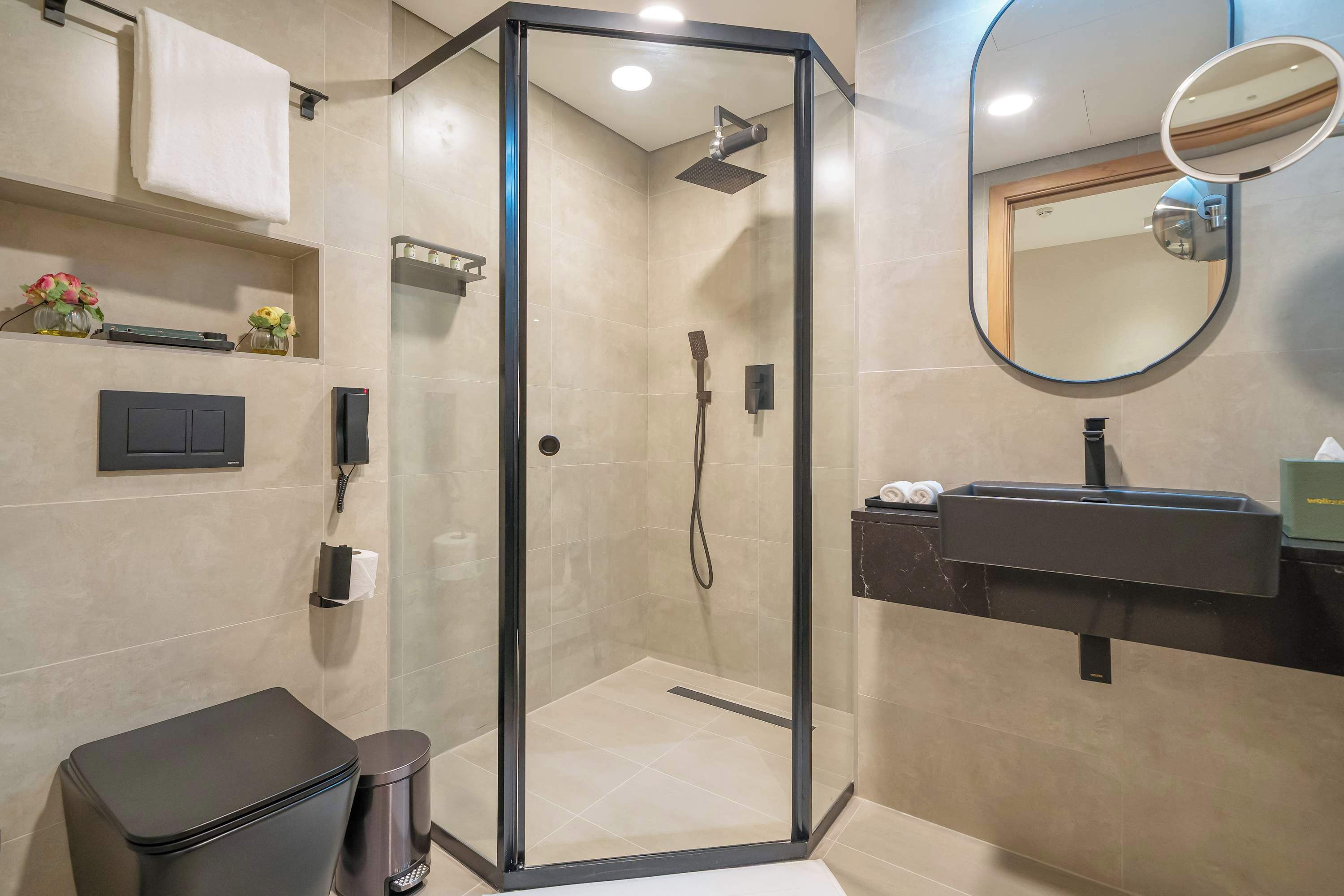 A modern bathroom with a glass-enclosed shower, a vanity with a mirror, and a toilet.