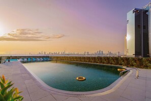 A rooftop swimming pool with a city skyline view, lounge chairs, and a lifebuoy. - Executive Wellness Suite | Sauna, Pool & Gym (Jumeirah Village Triangle)