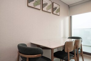 A conference room with a marble table, four chairs, and three abstract paintings on the wall. - Executive Wellness Suite | Sauna, Pool & Gym (Jumeirah Village Triangle)