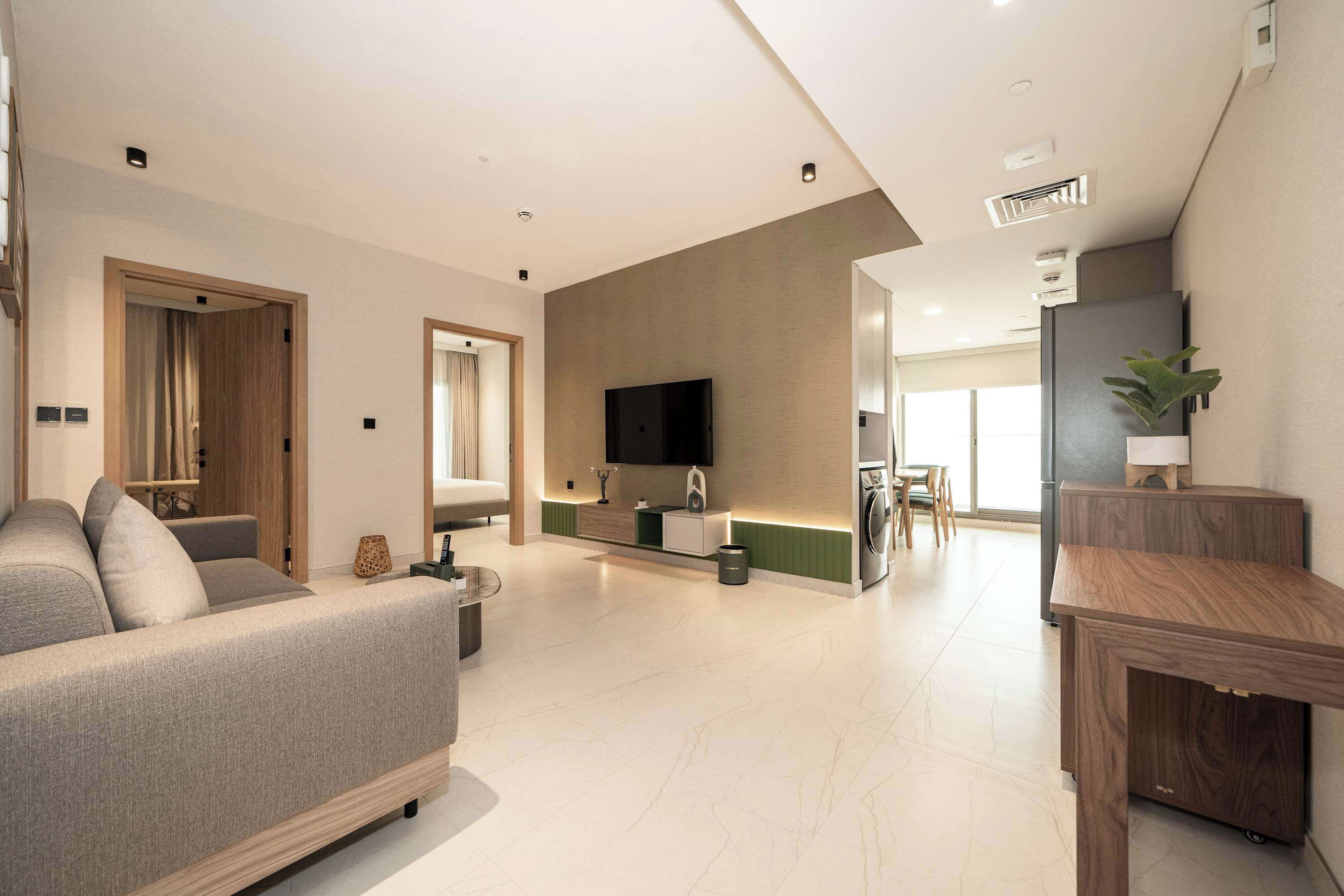 A modern living room with a sofa, a flat-screen TV, and a dining area with a table and chairs.