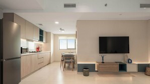 Eine moderne Küche mit integrierten Geräten, ein Essbereich mit Tisch und Stühlen sowie ein an der Wand befestigter Flachbildfernseher.