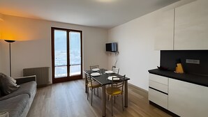 Eine moderne Küche mit Essbereich, einem flachbildfernseher über der Arbeitsfläche und Blick durch ein großes Fenster.