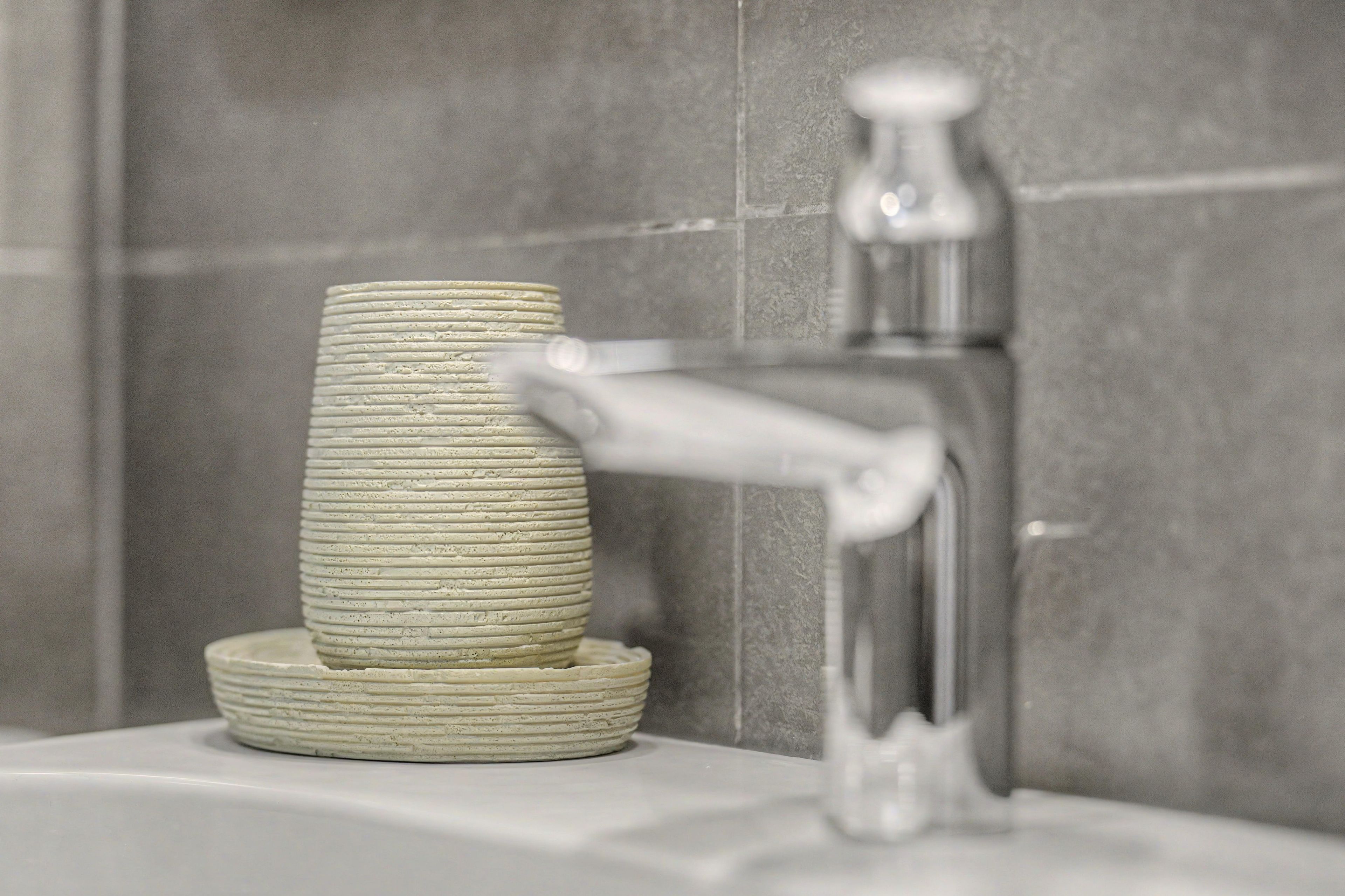 Een badkamer met een witte wastafel, een handdoekhouder en een waterkraan.