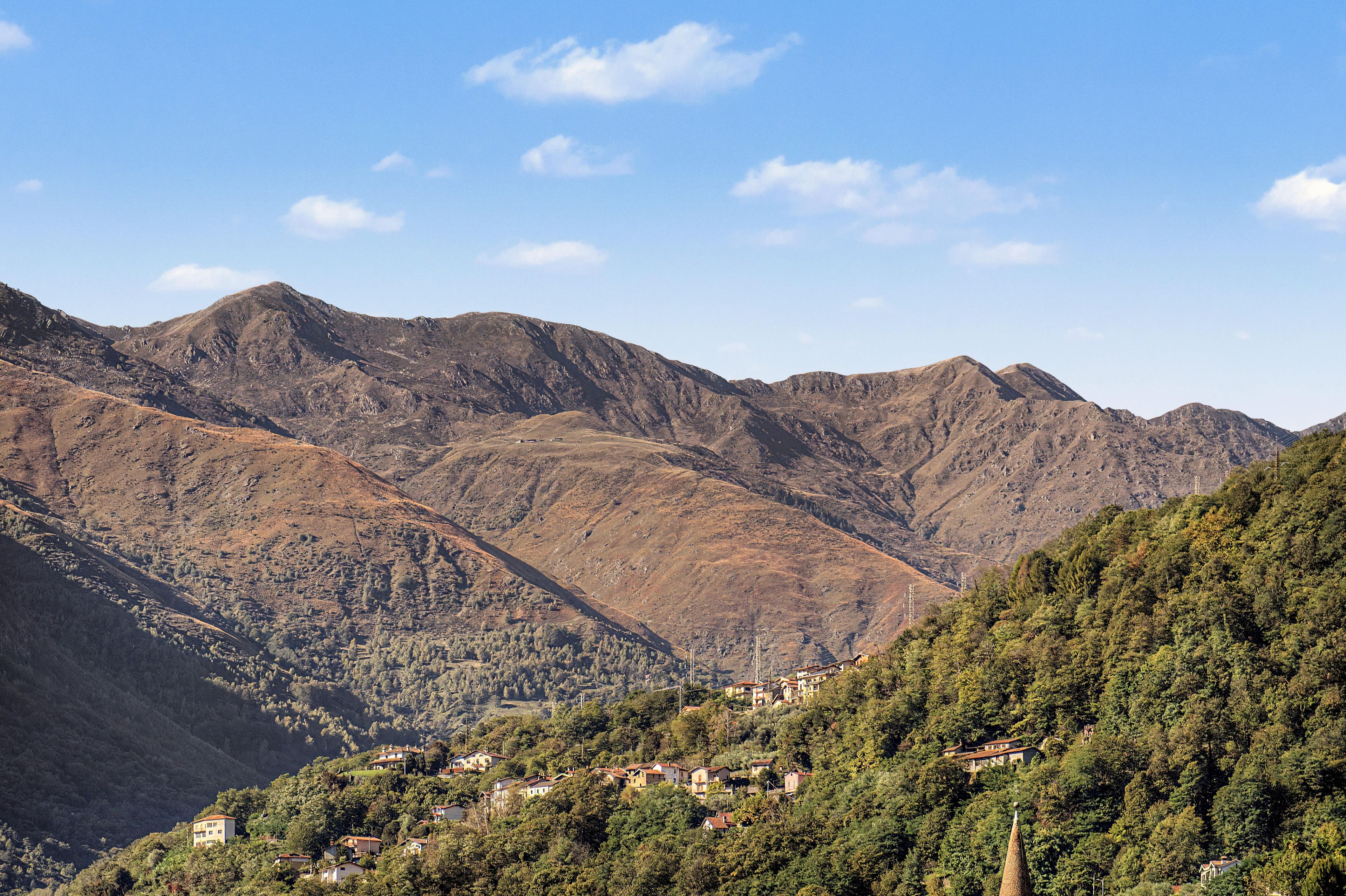 Paisagem montanhosa com um vale e um conjunto de casas numa encosta.
