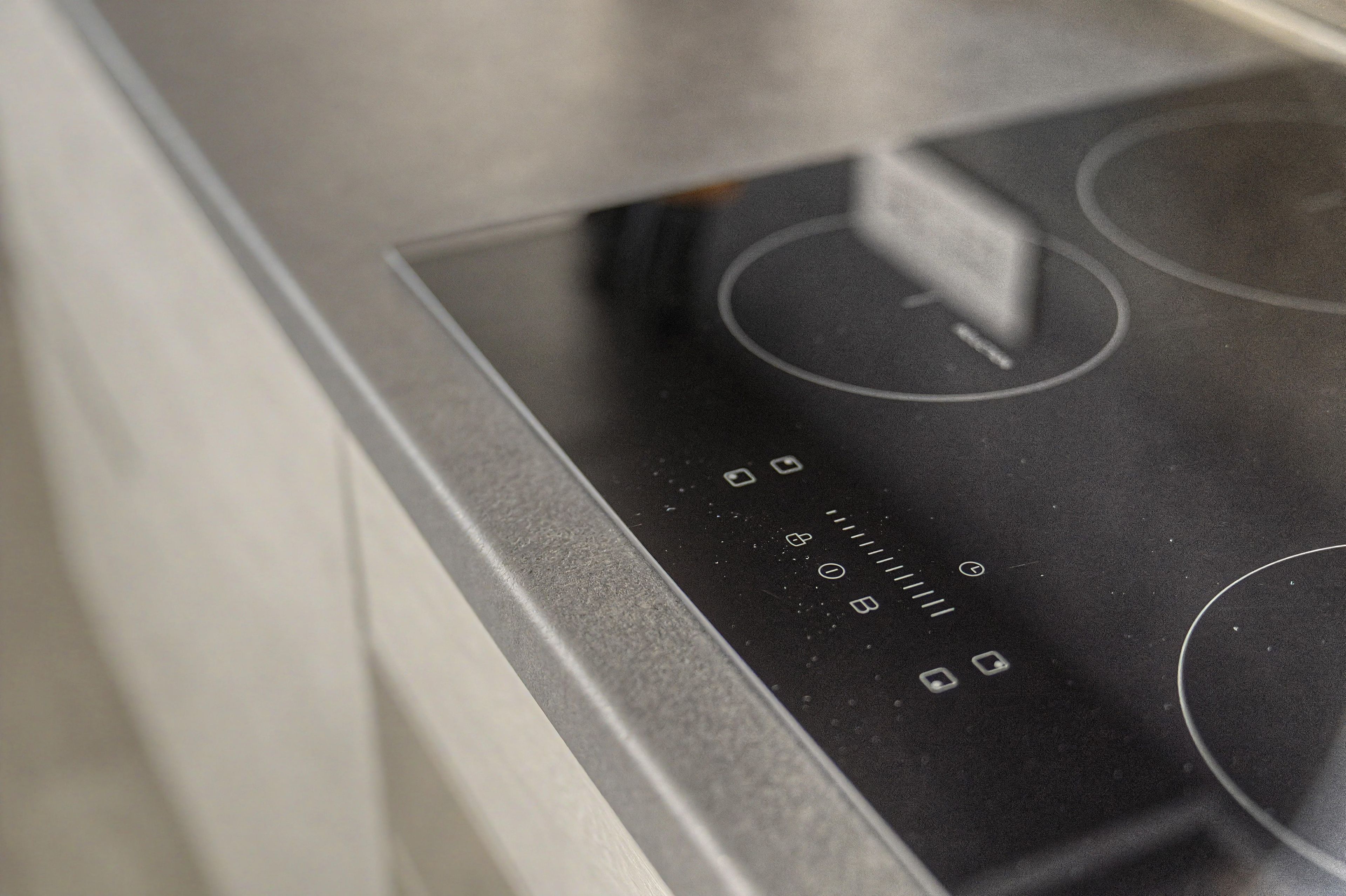 Gros plan d’une cuisine moderne avec une plaque de cuisson en acier inoxydable et un panneau de commande numérique.