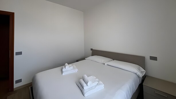 Ein Hotelzimmer mit einem Bett, zwei Kissen und zwei ordentlich gefalteten Handtüchern.