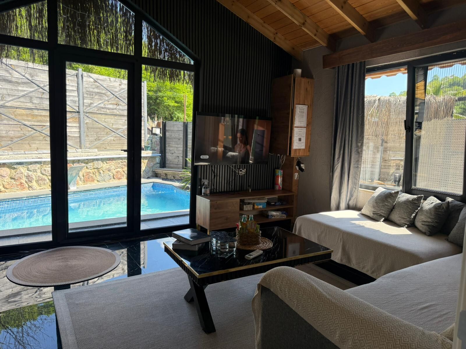 Una sala moderna con vista a la piscina, un televisor y una zona de estar confortable.