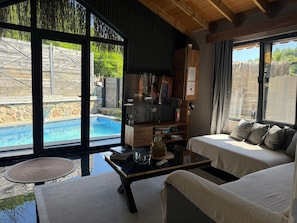 Una sala moderna con vista a la piscina, un televisor y una zona de estar confortable.