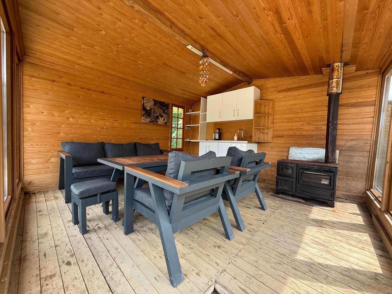 Un interior de madera con un sofá, una mesa y una zona de cocina con armarios y una estufa.