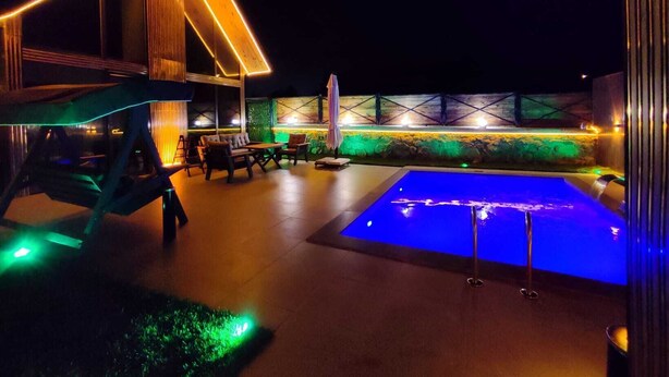 An outdoor area with a pool, seating, and a structure with illuminated edges.